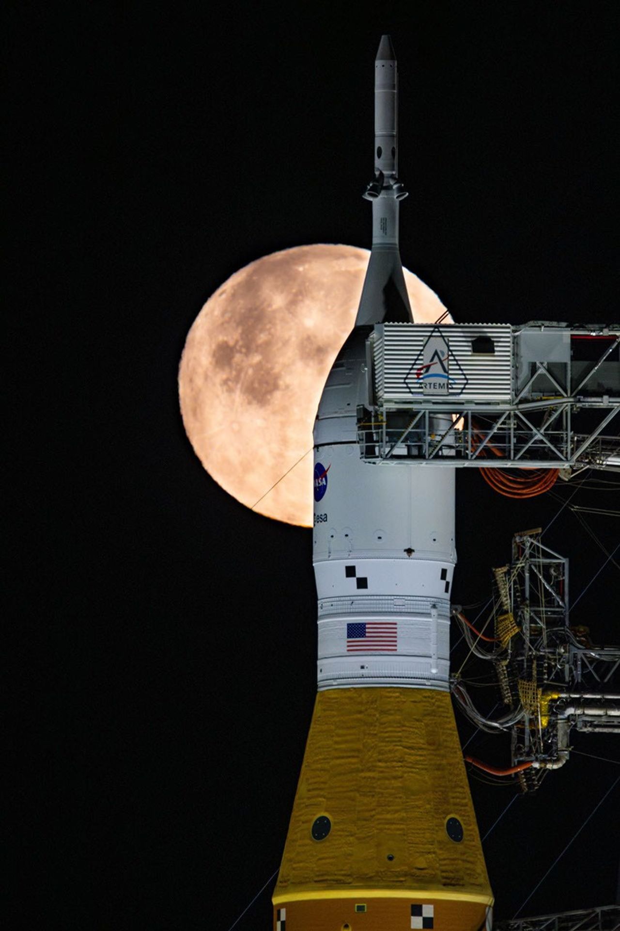Se ve una luna llena brillando sobre el Sistema de Lanzamiento Espacial (SLS, por sus siglas en inglés) de la NASA y la nave espacial Orion, montados sobre la plataforma de lanzamiento móvil, en las primeras horas del 1 de febrero de 2026.