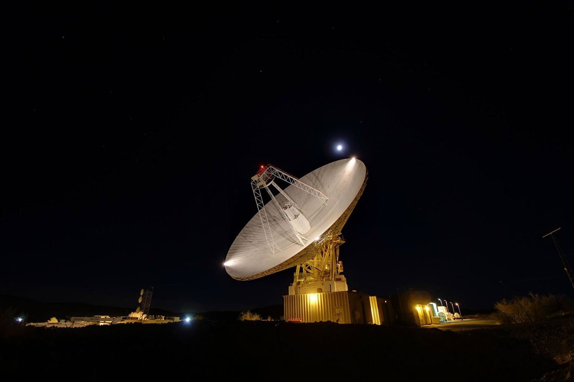 La antena de 70 metros (230 pies) de Goldstone rastrea bajo una luna llena. El Complejo de Comunicaciones del Espacio Profundo de Goldstone está ubicado en el desierto de Mojave en California, EE.UU.