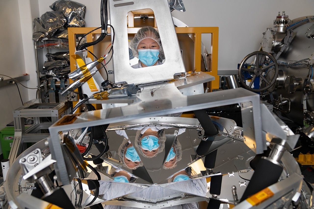 Amelia Quan, líder de integración mecánica para la misión SPHEREx de la NASA, aparece aquí con un radiador de ranura en V, una pieza de hardware que ayudará a mantener frío el telescopio espacial.