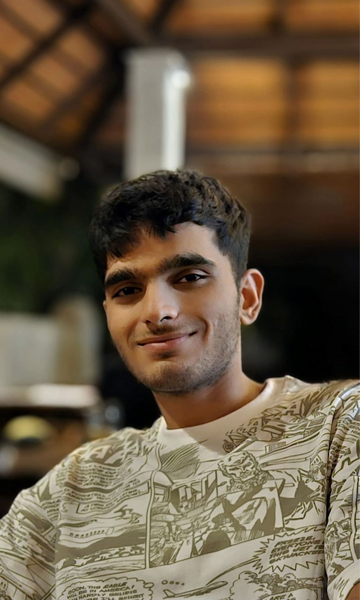 Portrait of a smiling person with dark hair sitting indoors..