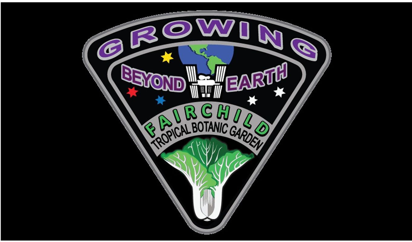 A shield-shaped emblem with a black background and a silver border. At the top, purple arched text reads "GROWING". Below that, the text "BEYOND EARTH" flanks a drawing of the International Space Station with the Earth behind it, surrounded by colorful stars. At the bottom, the text "FAIRCHILD TROPICAL BOTANIC GARDEN" arcs over an illustration of a leafy green vegetable, like bok choy.