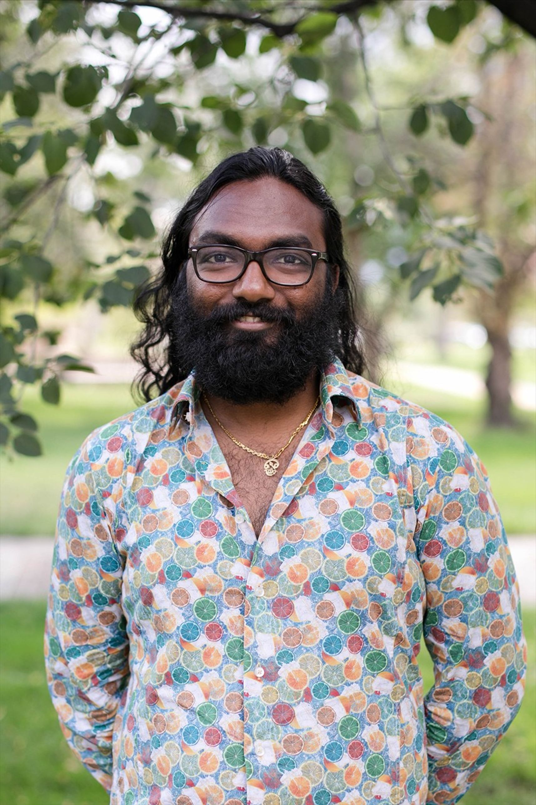 Portrait photo of a smiling man standing in a park like setting