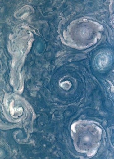 Swirling cloud formations on Jupiter's surface, showcasing intricate patterns of storms and vortices in shades of blue and white, captured from a high-resolution space image.