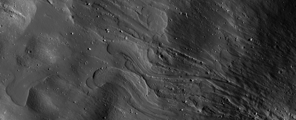 Black and white image shows now-frozen grey lobes of flow that came from the lower right. Sunlight boulders moved by the flow appear as irregular white lumps.