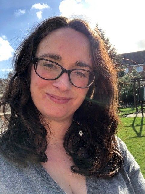 Photo of a smiling woman with long dark hair and glasses