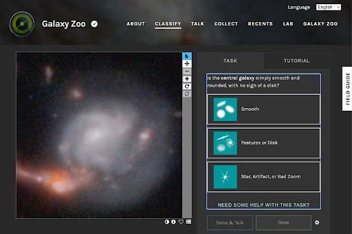 On a black background under the header of “Galaxy Zoo” and the projects navigation tabs About, Classify, Talk, Collect, Recents, Lab, and Galaxy Zoo, we see an image of a fuzzy, silver, spiral-armed galaxy on the left. On the right a question prompts the viewer to classify the image as smooth, with features or disks, or a star, artifact, or bad zoom image.
