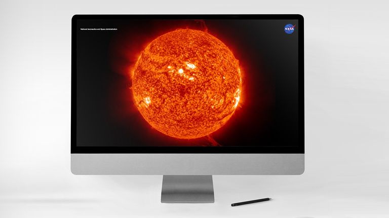 A bright orange solar eruption image on the screen of a desktop computer