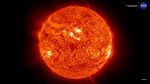 Close-up image of the Sun’s surface showing a mottled texture of glowing orange plasma, bright active regions, and several looping solar prominences extending from the edges into space.