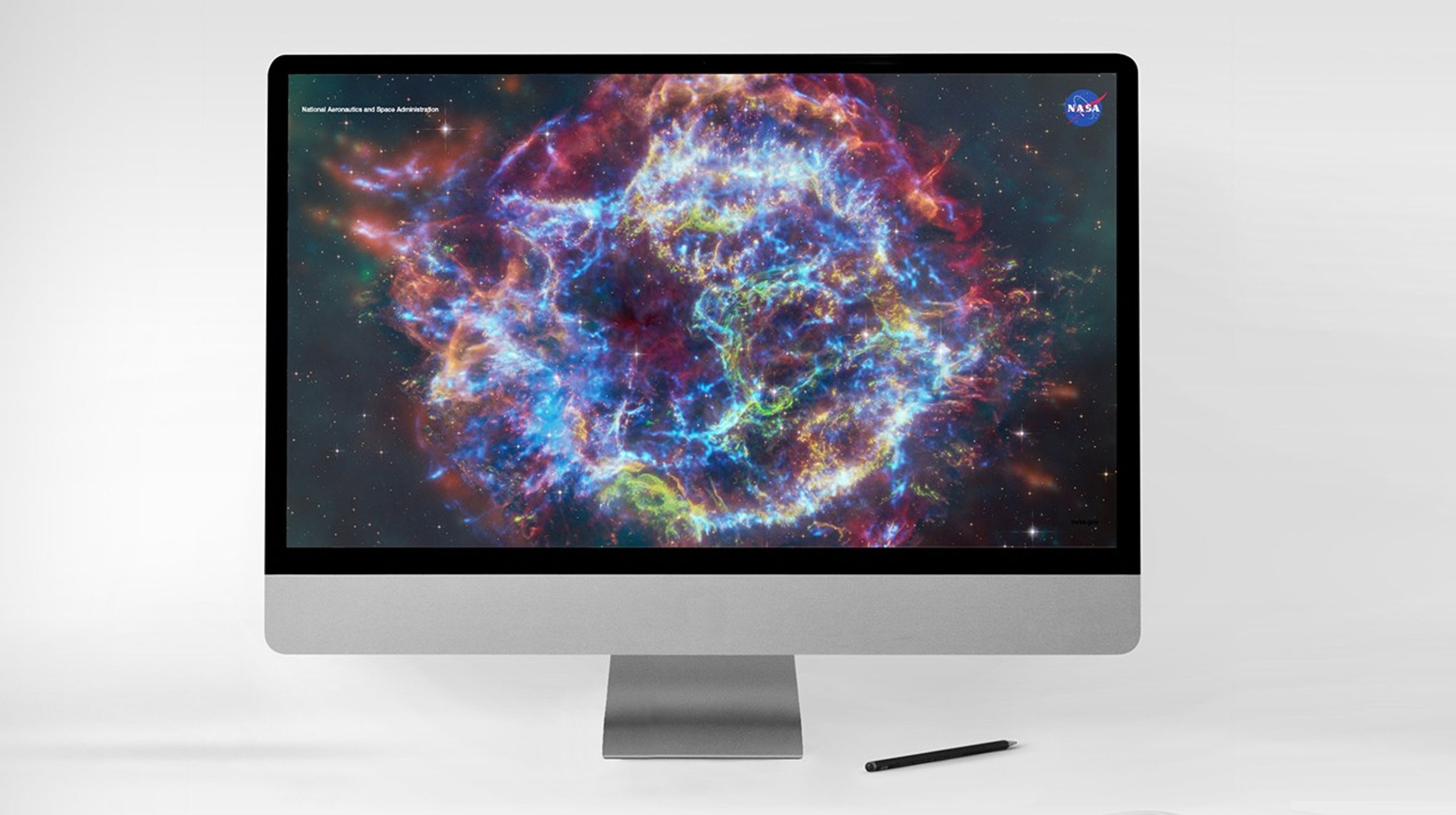 Un monitor de computadora de escritorio muestra una colorida imagen compuesta del remanente de supernova Casiopea A.