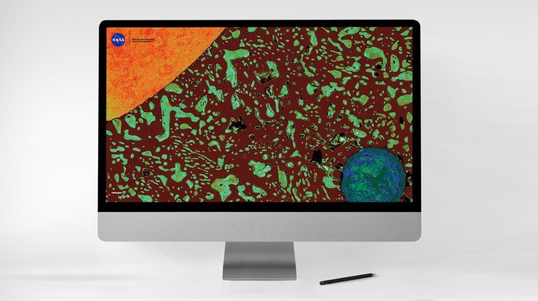  Una computadora de escritorio gris sobre fondo blanco muestra la una imagen en la que se aprecia una imagen de microscopio. Se aprecia una sección transversal microscópica de una gota de soldadura que muestra un cable de cobre (naranja, arriba a la izquierda) y vacío (círculo azul verdoso, abajo a la derecha) rodeados por material de soldadura de color marrón oscuro y azul verdoso, que se asemeja a un sistema solar con el cable como el sol y el vacío como la Tierra.