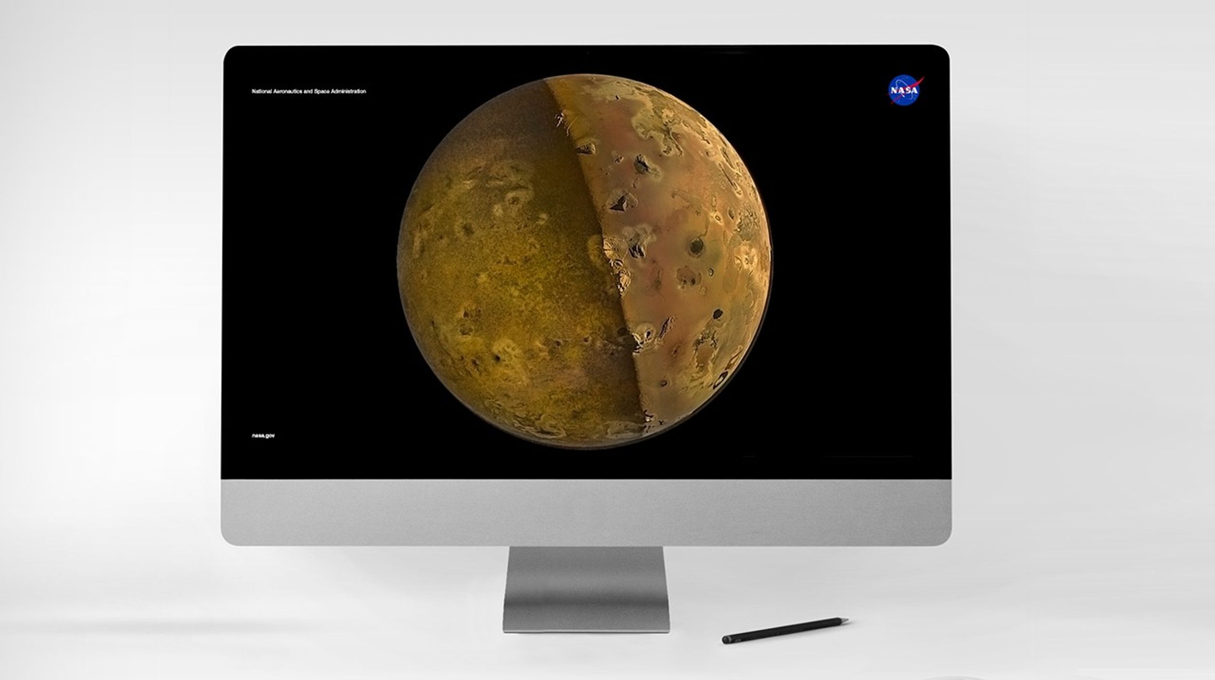 Jupiter's moon Io appearing golden-tan against the blackness of space, half the moon bathed in shadow, half in light, bisected vertically, with mountain peaks and volcanos pockmarking the surface.