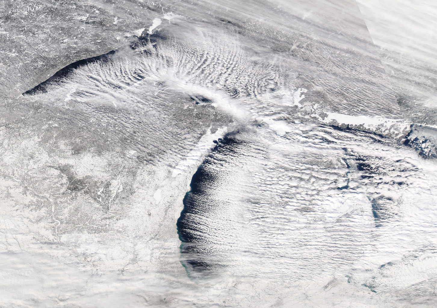 An image from space of the Great Lakes region of the United States showing significant snowfall.