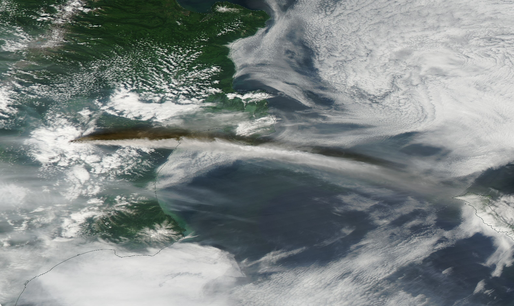 A view from orbit above Russia's Kamchatka Peninsula showing a plume of ash and smoke traveling eastward.