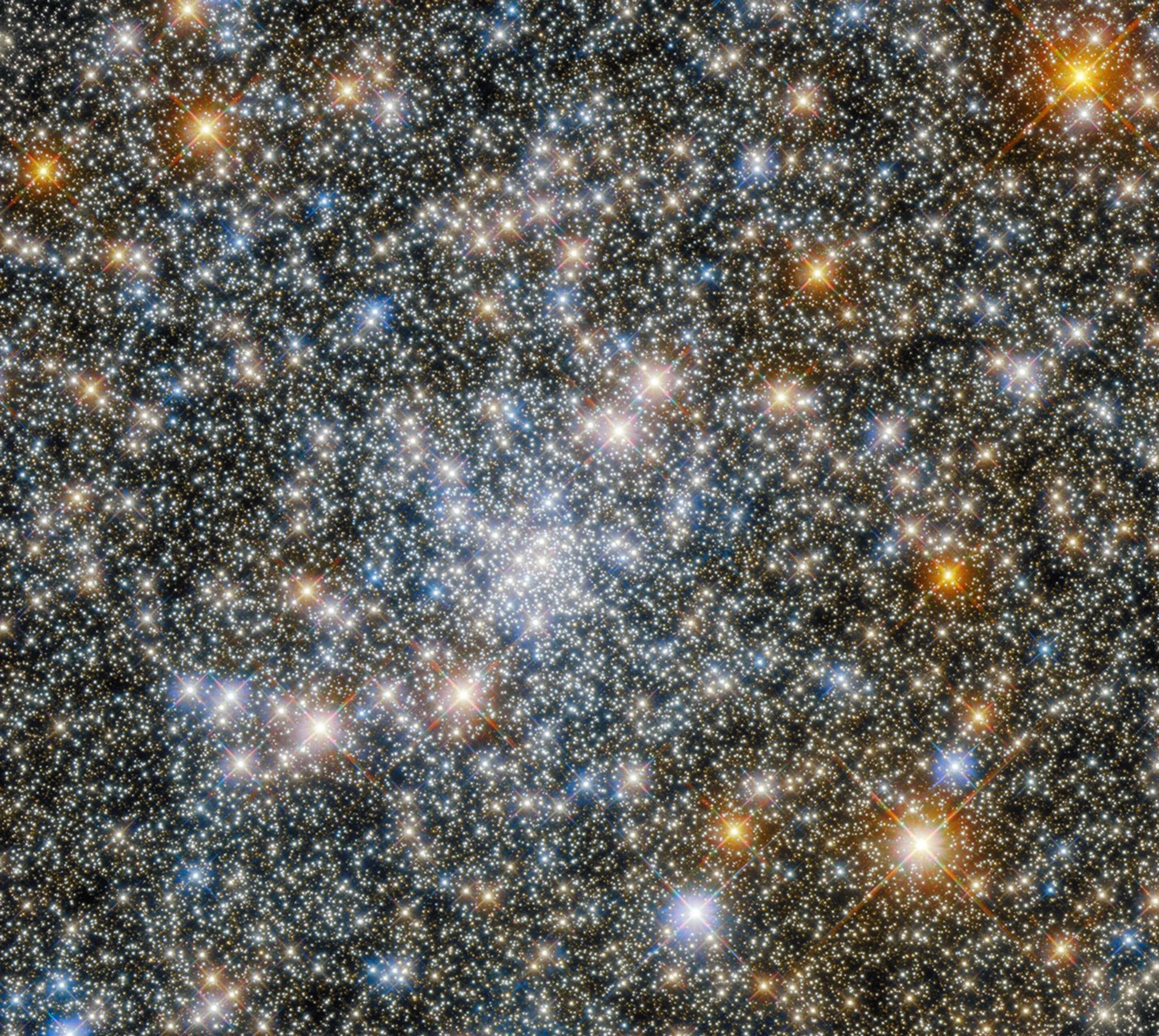 Stars fill the image. bright, blue-white stars are concentrated in the image's center. large, gold stars dot the scene.