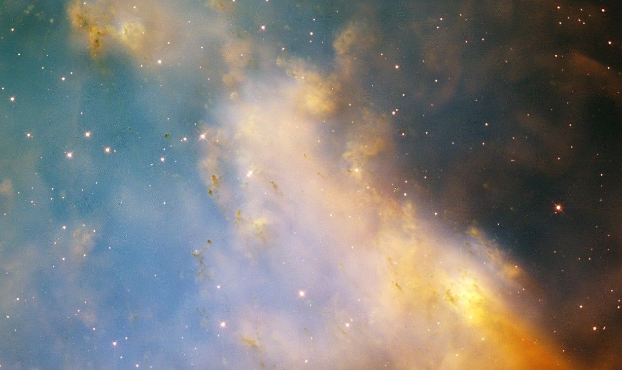 Nubes de polvo y gas en tonos de azul, amarillo y marrón oscuro que conforman una porción de la nebulosa de la Mancuerna. 
