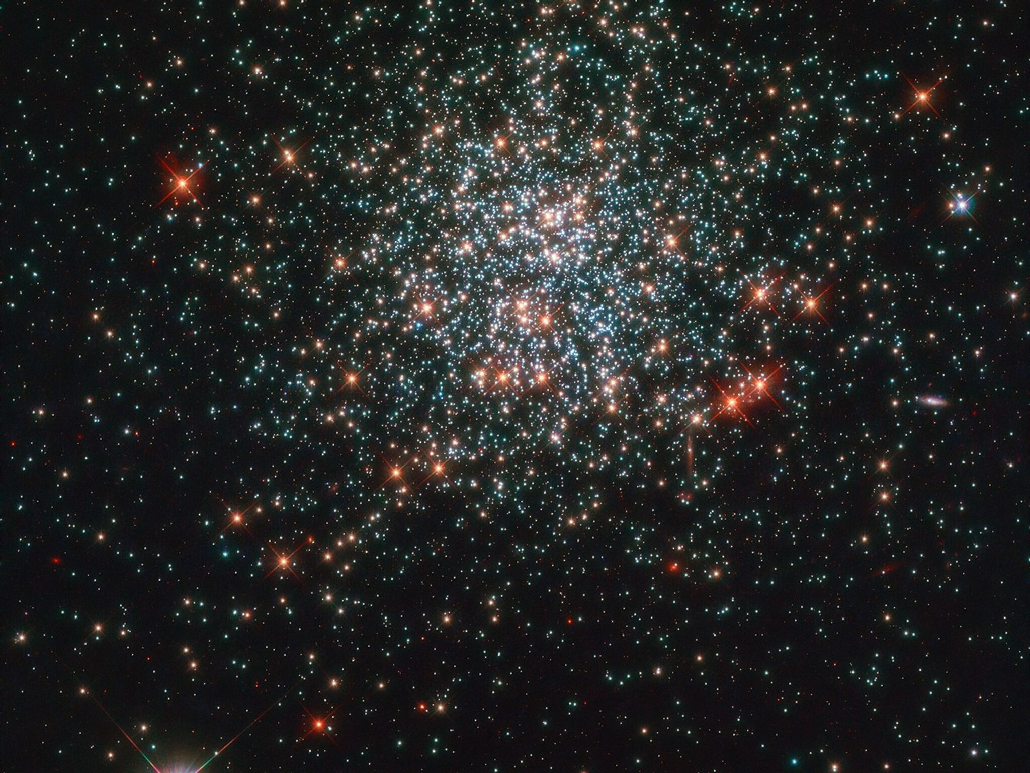 Bright specks of white and red stars against black backdrop of space