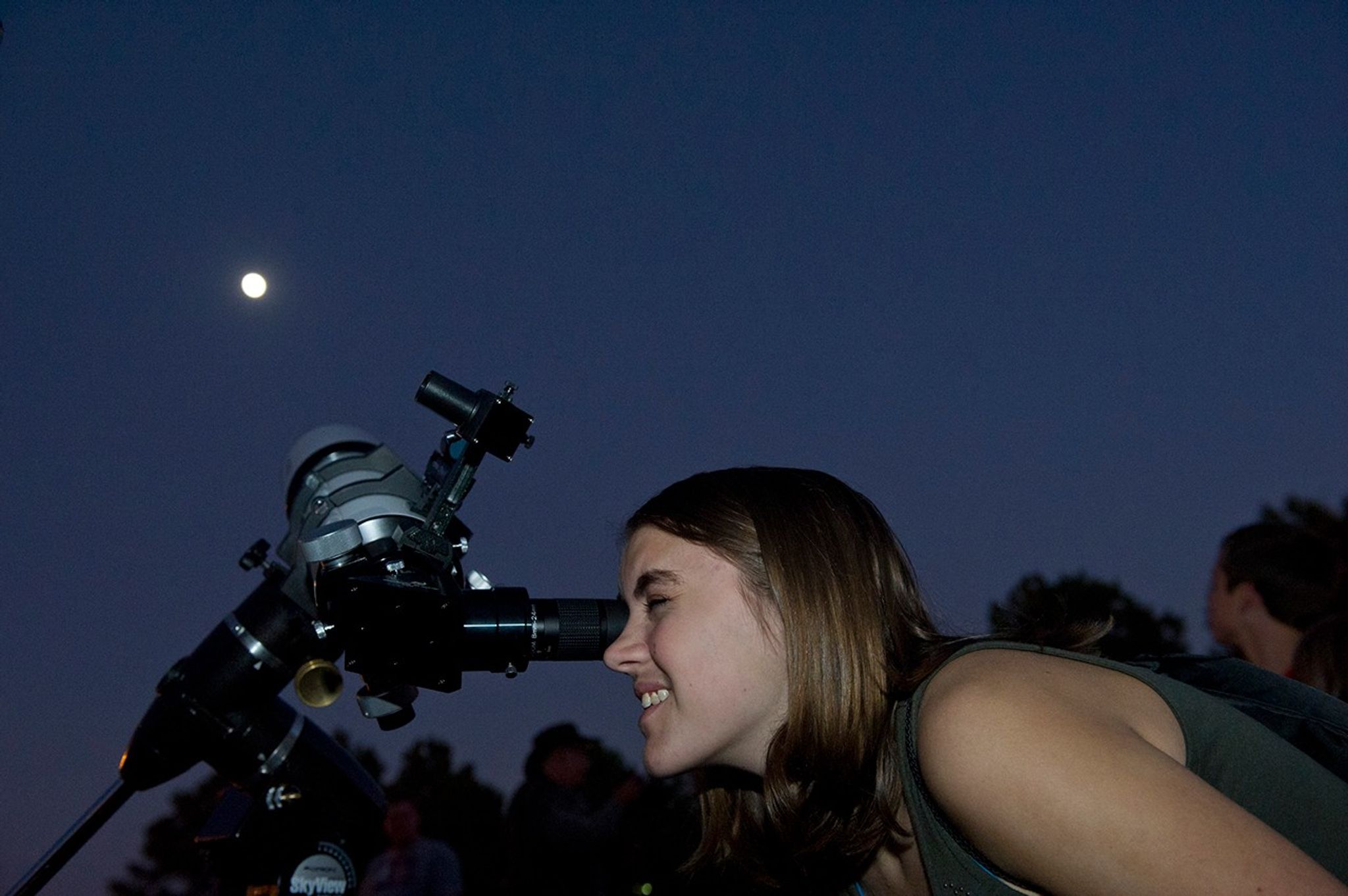 Una mujer observa la Luna a través de un telescopio.