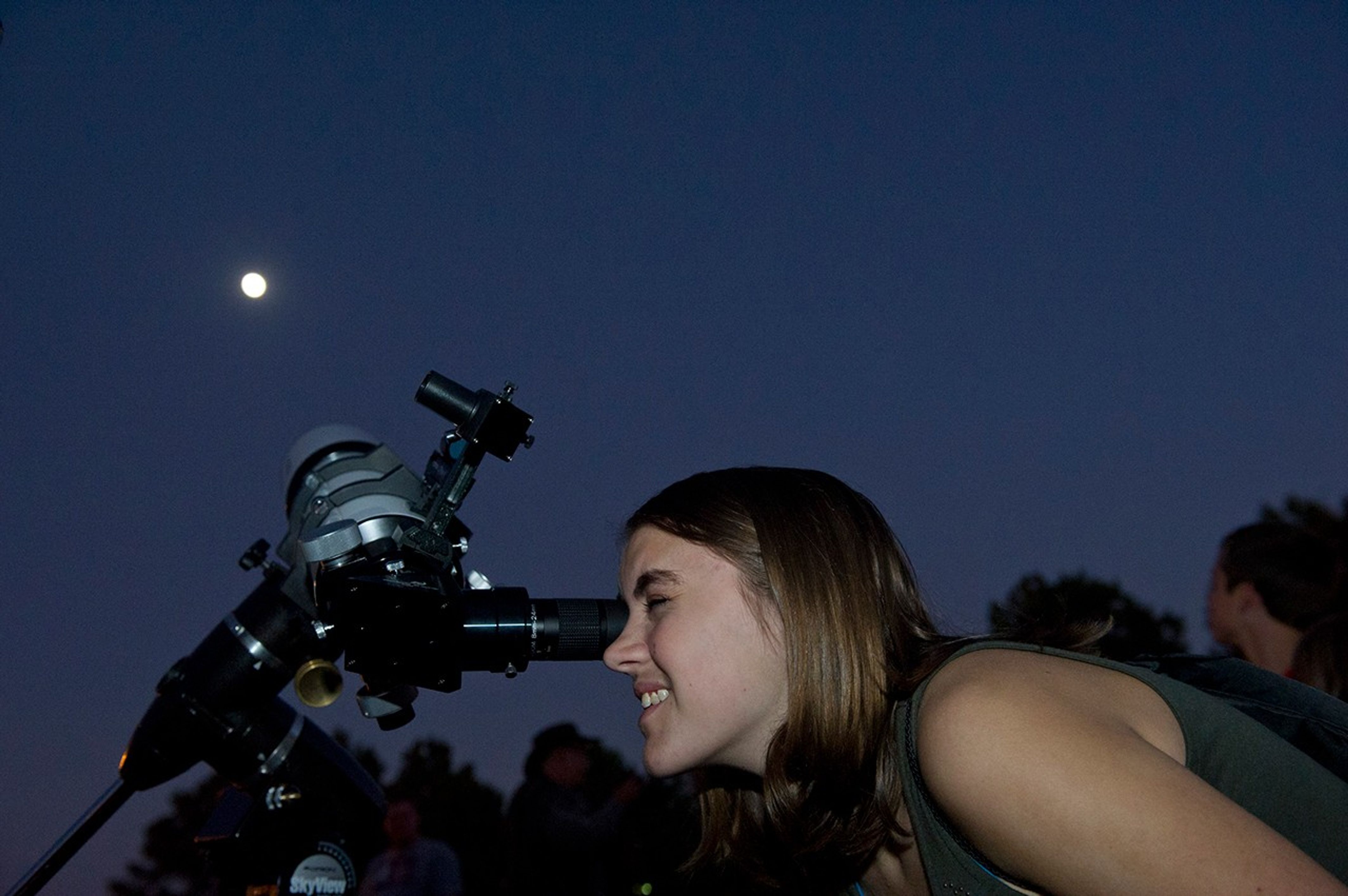 Una mujer observa la Luna a través de un telescopio.