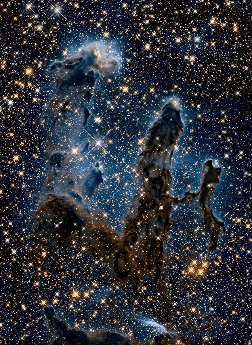 Los Pilares de la Creación en la nebulosa del Águila, captados en luz visible por el telescopio espacial Hubble. En el infrarrojo, la luz de las estrellas jóvenes que están formándose atraviesa las nubes de polvo y gas.
