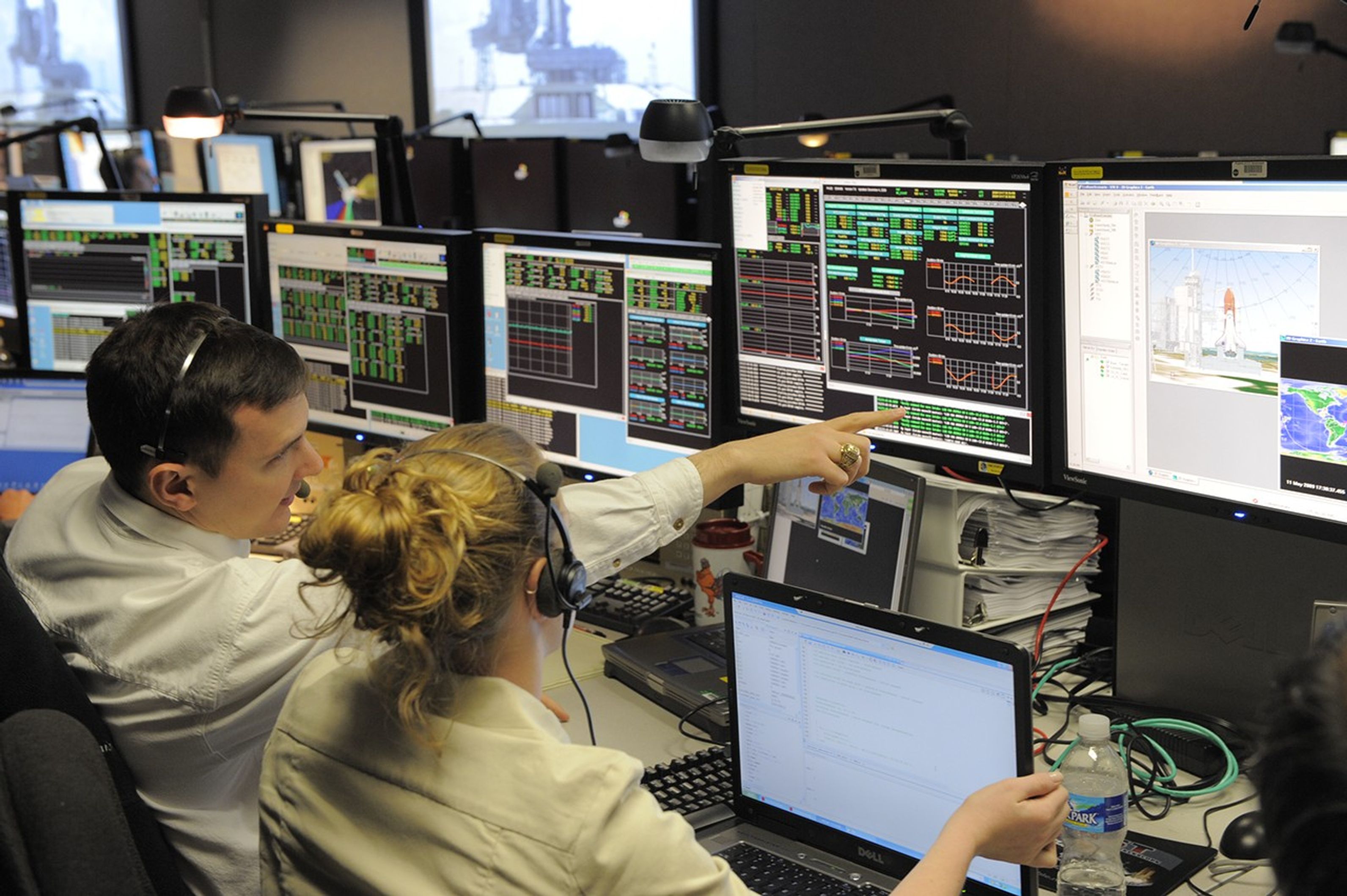 Two engineers talk in the Hubble control center waiting for the Shuttle to launch