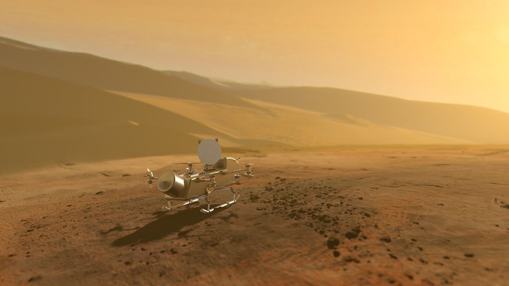 Dragonfly rotorcratf facing away on the rust-orange surface with giant dunes in the background and a hazy yellow sky