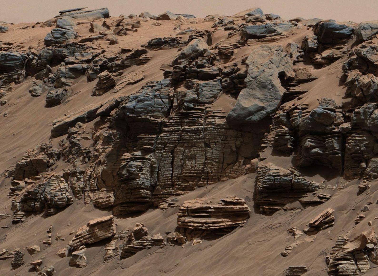 sta roca de capas uniformes, fotografiada por el sistema Mast Camera (Mastcam) instalado en el rover Curiosity de la NASA en Marte, muestra un patrón típico de depósito sedimentario de fondo lacustre, situado no muy lejos de donde el agua fluía hasta desembocar en un lago.
