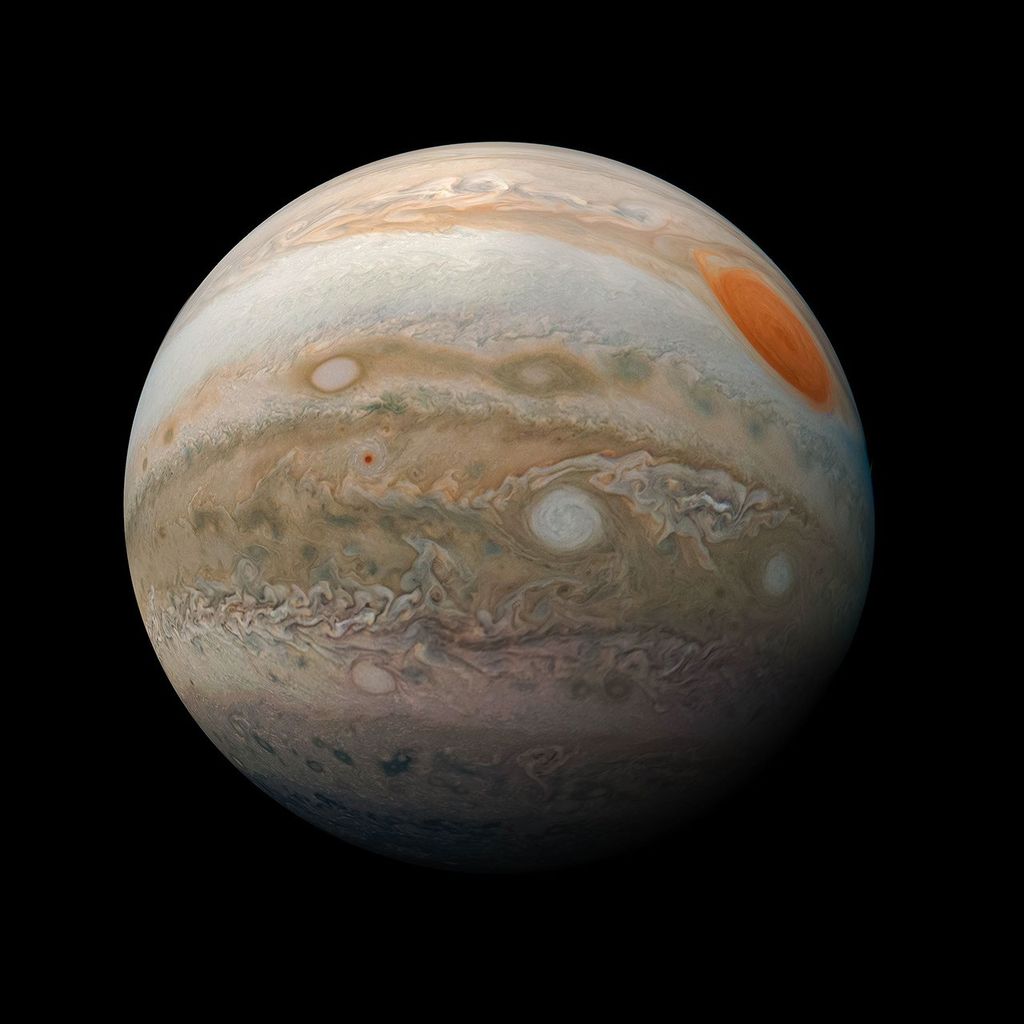 A view of one side of Jupiter showing its Red Spot and tan, orange, and white bands of clouds.