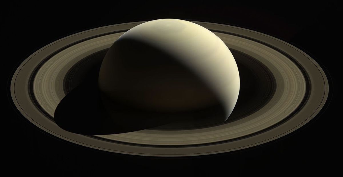Saturn backlit by the Sun photographed by Cassini spacecraft in its final farewell image showing rings in silhouette and Earth as a pale blue dot