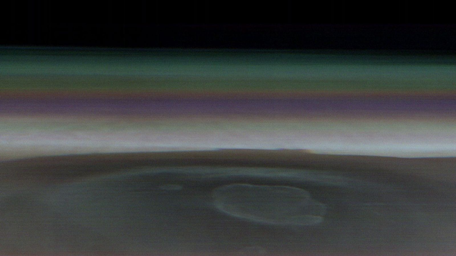 Different colored bands of atmosphere extend across the peak of a massive extinct volcano on Mars.