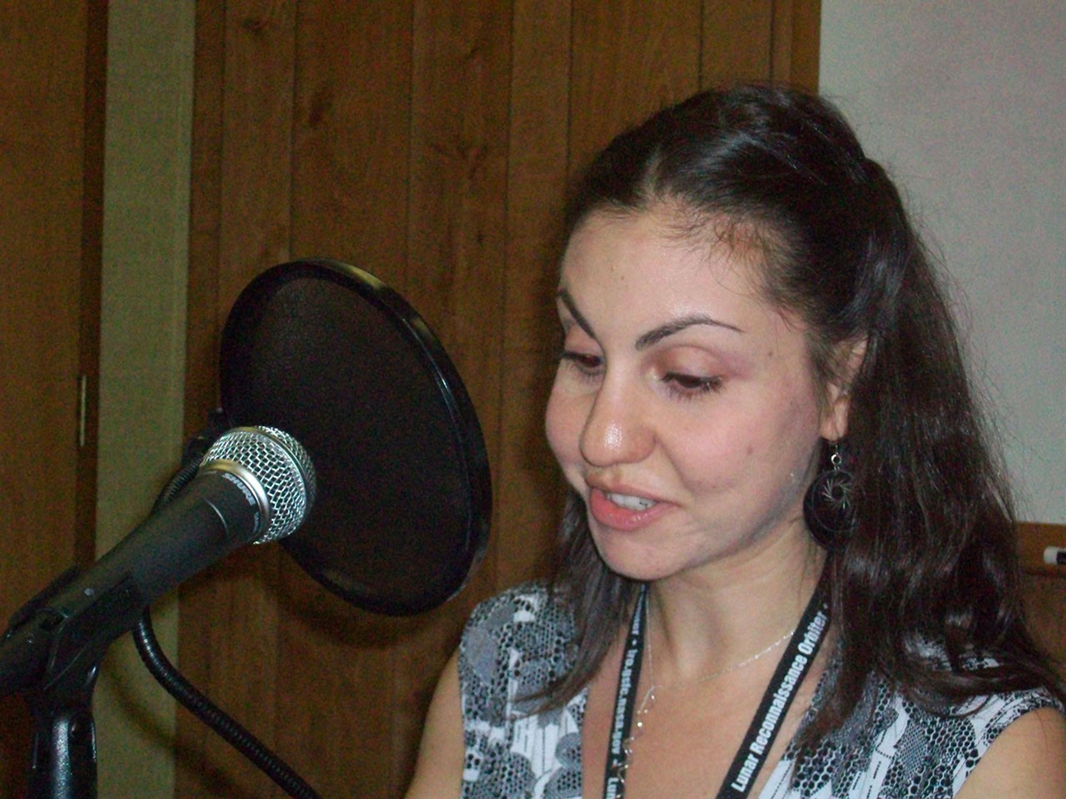Svet in front of a microphone narrating a podcast.