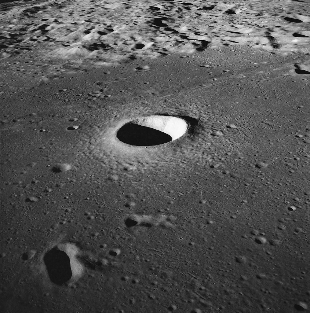 El cráter Moltke es un pozo de sombra y luz en una porción relativamente plana de la superficie de la Luna, rodeado a lo lejos por más cráteres y crestas.