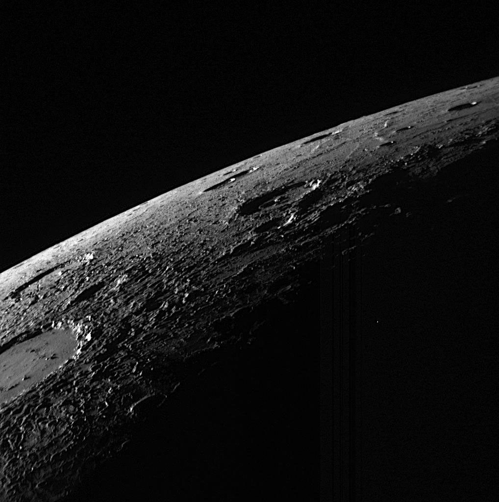 The northern portion of the sunlit, crescent-shaped surface of Mercury is seen from the MESSENGER spacecraft as it approached the planet. The low Sun angle creates distinct shadows, enhancing the visibility of the roughness of the surface, which is especially prominent for material ejected from, and surrounding, the impact crater cut by the left edge of this image.
