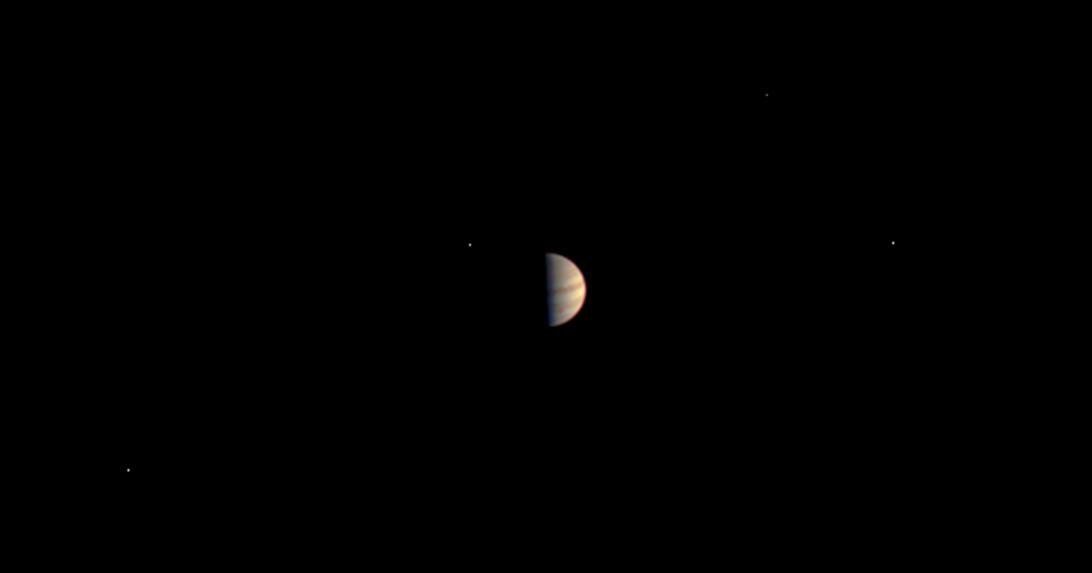 Jupiter appears small and partially lit with bright dots nearby. The dots are Jupiter's four largest moons.