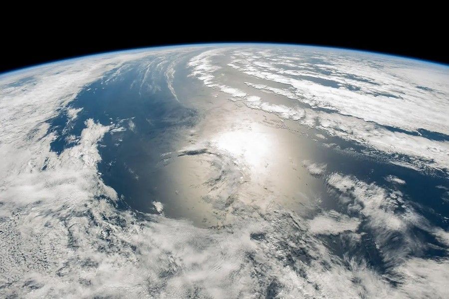 An image looking down onto a limb of the Earth showing clouds over the ocean.