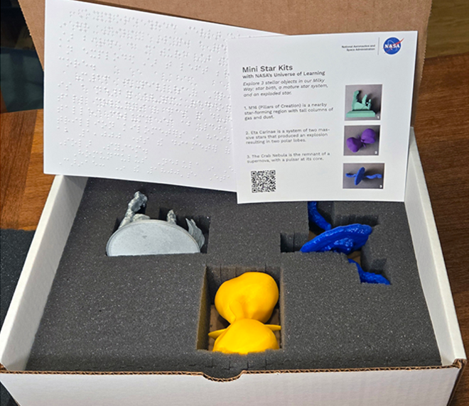 Photo of the 3D printed mini star kits sent to the Library of Congress state library hubs. The box shows three 3D printed models of stars, and descriptive handouts with text and braille.