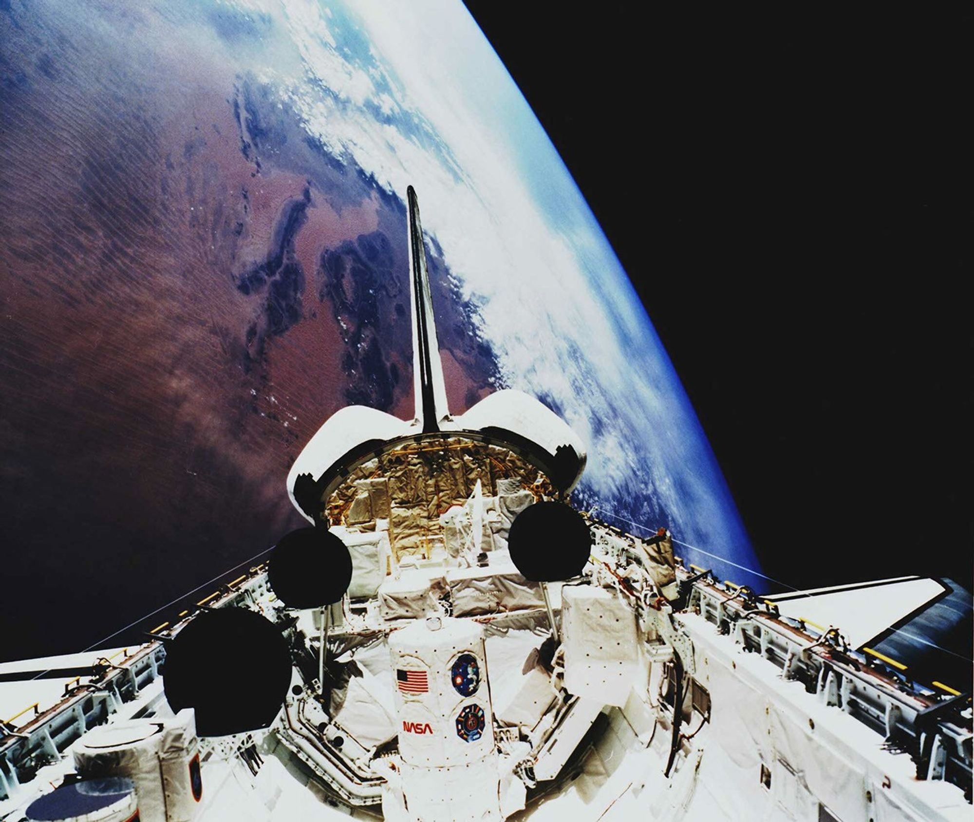 A space shuttle in orbit with its payload deployment doors open.
