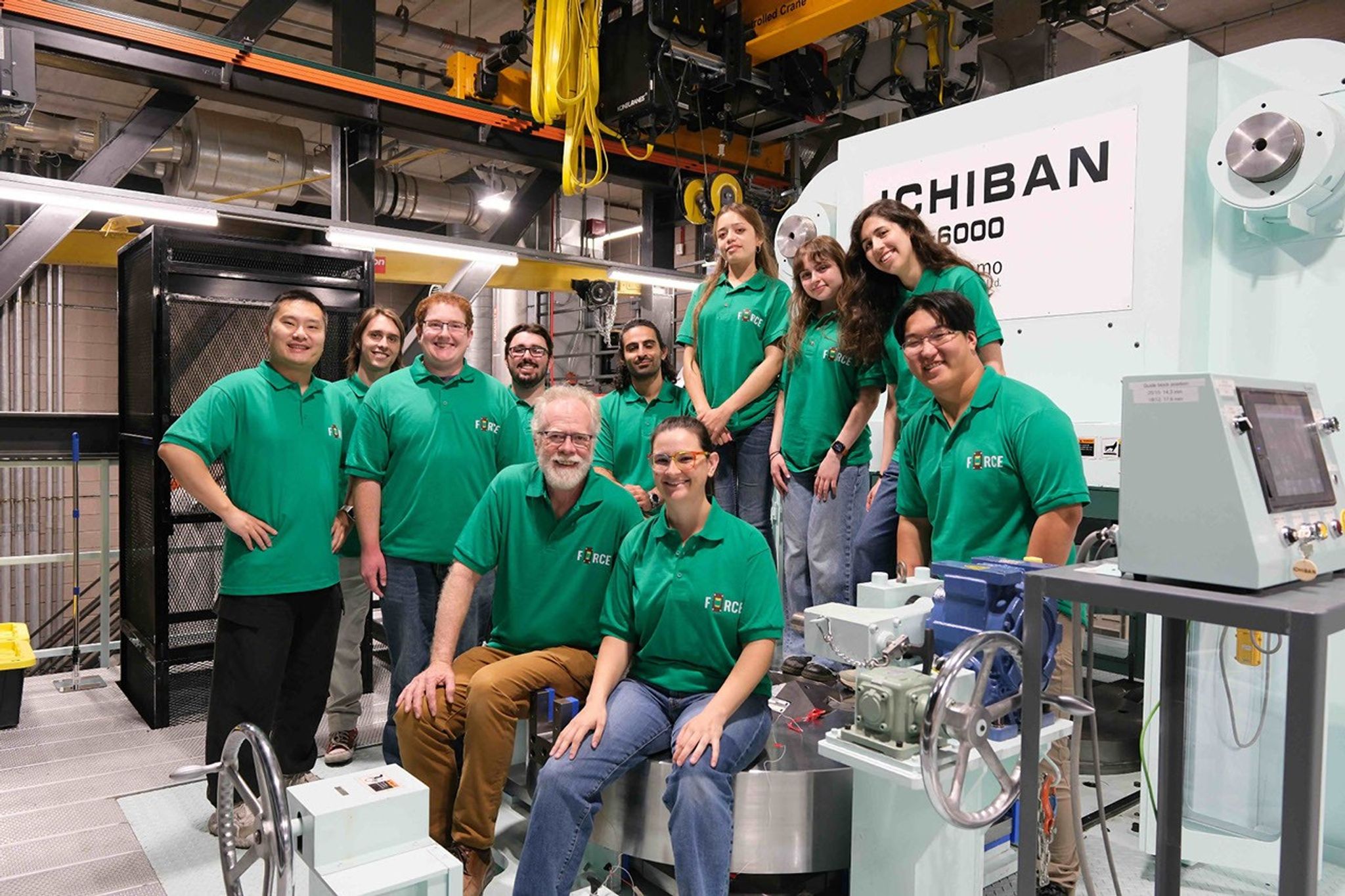 Undergraduate research interns and FORCE leaders pose together beside the Ichiban high-pressure machine and other laboratory equipment.