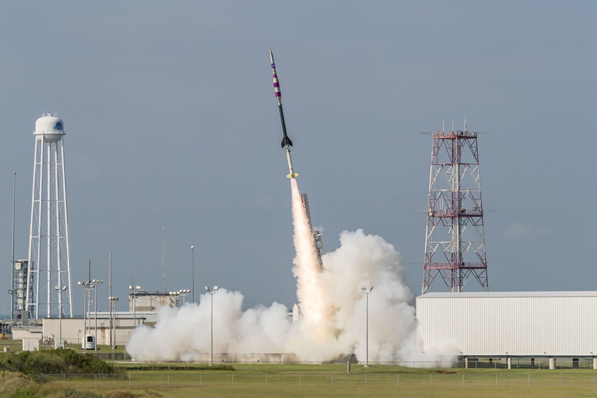 A suborbital sounding rocket launches from a launch pad with a plume of smoke undeneath.