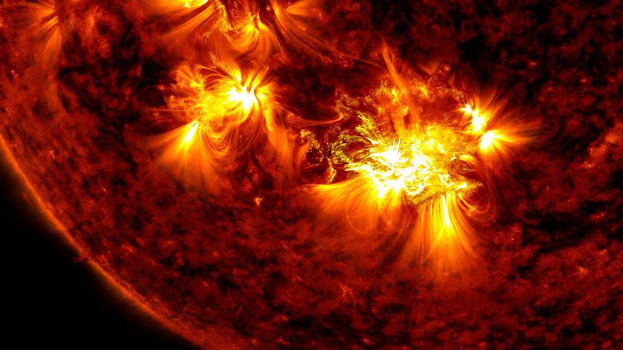 A small portion of the Sun is shown in shades of red, black, and yellow. Two bright yellow regions appear in contrast to the surrounding areas, which appear as patches of dark red and black.