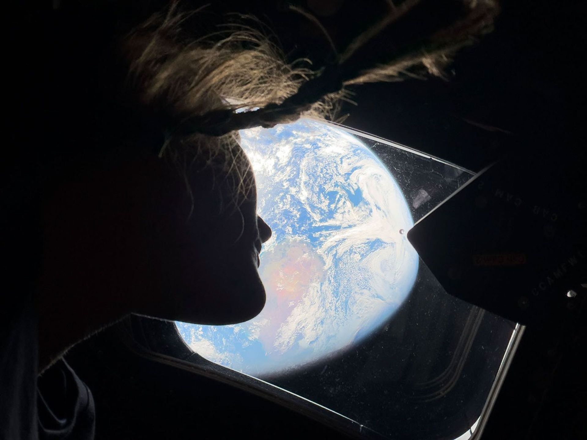 La astronauta de la NASA Christina Koch mira hacia la Tierra desde una de las ventanas de la nave espacial Orion de Artemis II de la NASA.