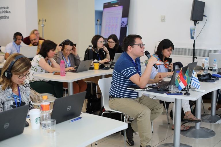 People seated at tables during a 2022 workshop in Buenos Aires. In the foreground, DINAGUA supervisor Jose Rodolfo Valles León holds a microphone, while members of the Uruguay delegation sit behind him.