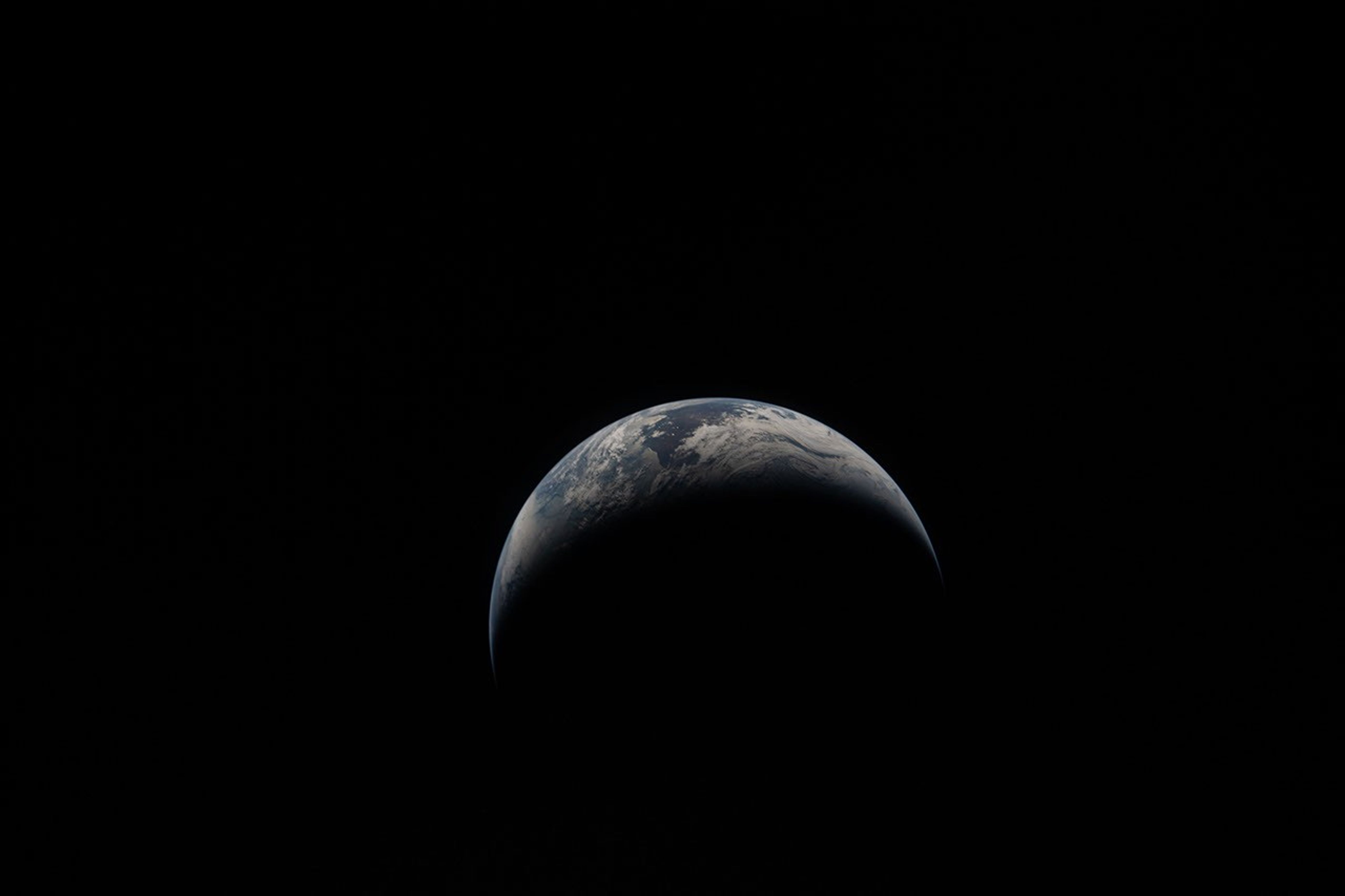 A portion of Earth glows faintly against the dark background of space.