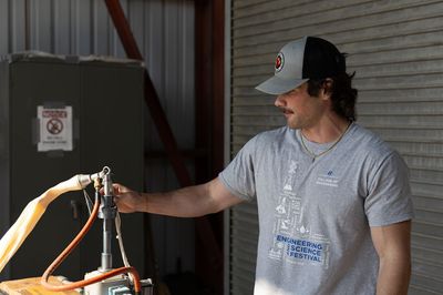 A man attaches a large balloon to a nozzle, filling it with hydrogen gas.