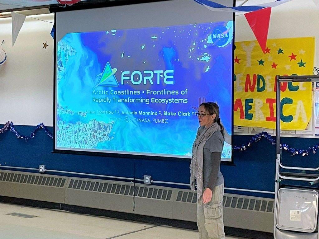 A woman makes a slide show presentation in a community hall.