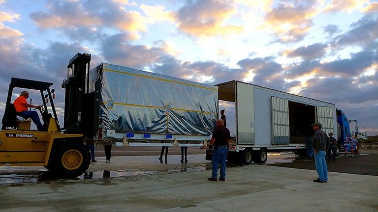 The transportation canister containing NASA's Soil Moisture Active Passive (SMAP) spacecraft is offloaded from the truck that delivered it from NASA's Jet Propulsion Laboratory in Pasadena, California, to the Astrotech payload processing facility on Vandenberg Air Force Base in California. Credit: NASA/JPL-Caltech