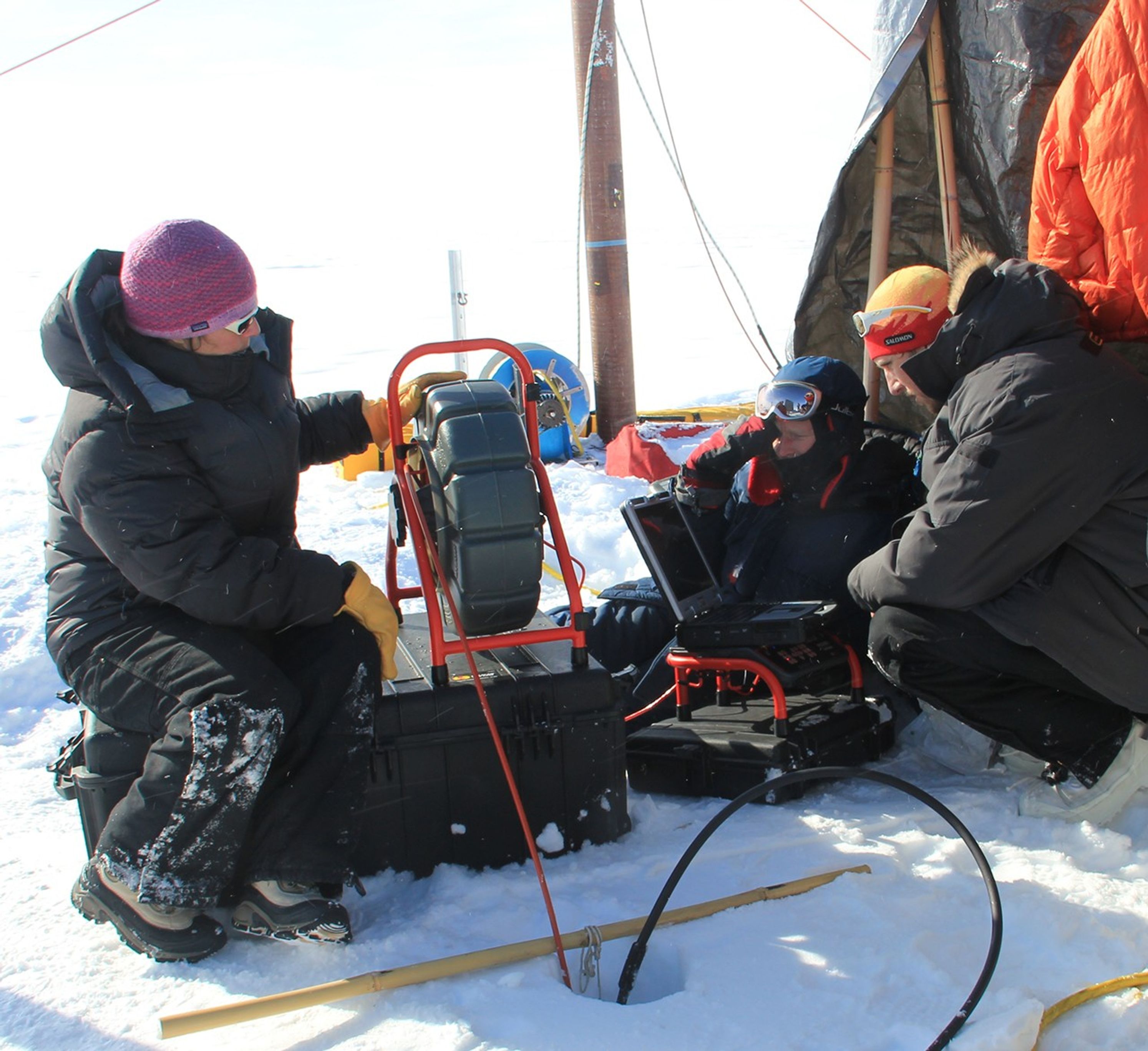 Glaciologist Lora Koenig (left) operates a video recorder that has been lowered into the bore hole to observe the ice structure of the aquifer in April 2013.