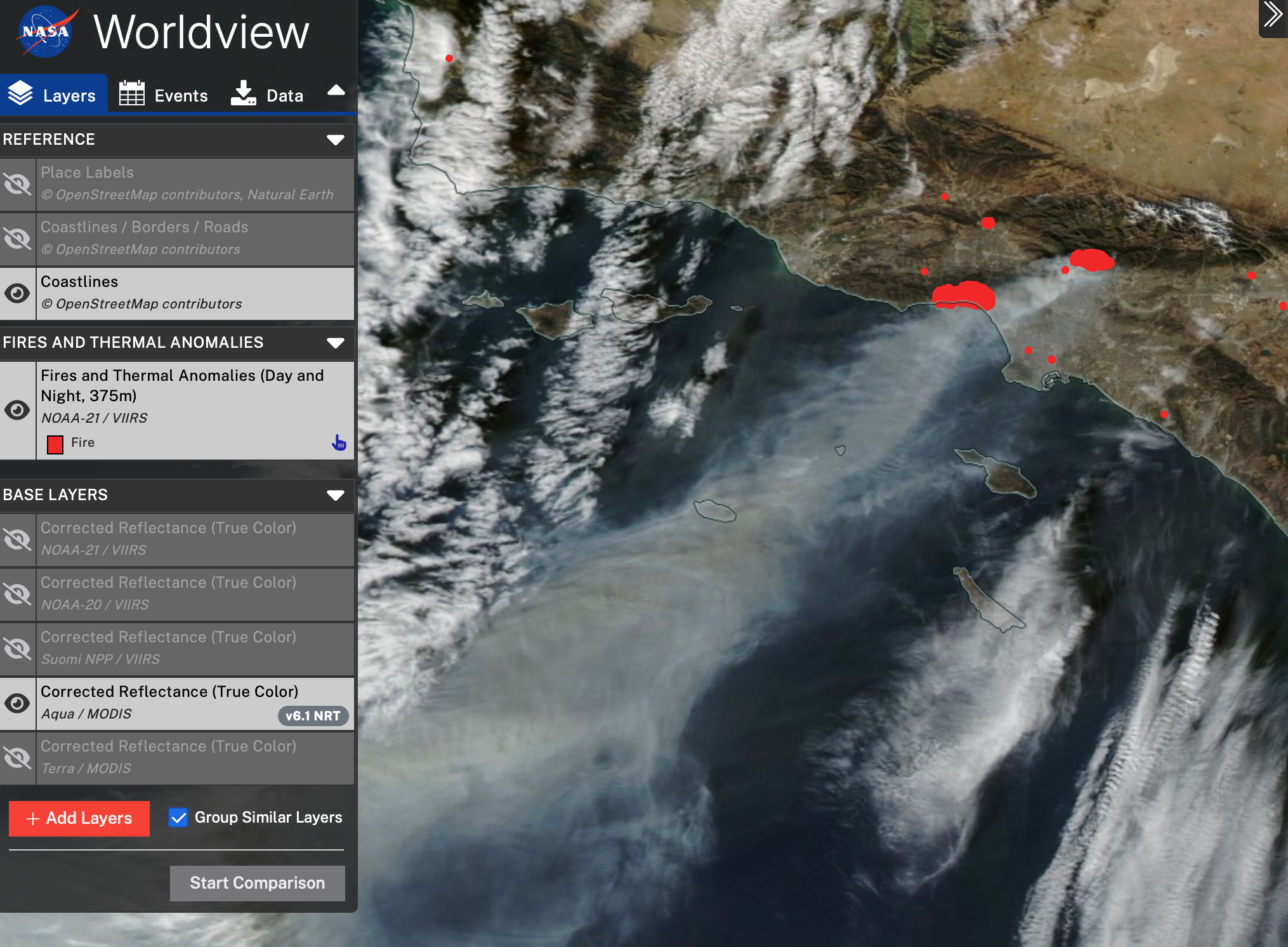 A screenshot of NASA’s Worldview tool, showing a satellite image of southern California during the L.A. fires on Jan. 8, 2025. The landscape is a mixture of greenish-brown colors and the Pacific Ocean is dark blue. Two large clusters of red dots show the Palisades fire and the Eaton fire, with smaller clusters of dots throughout the area. Plumes of gray smoke come from the fires and head offshore. A few areas of white clouds are visible, in contrast to the gray smoke. The upper left side of the image contains the Worldview menu with various data layers the user can select.
