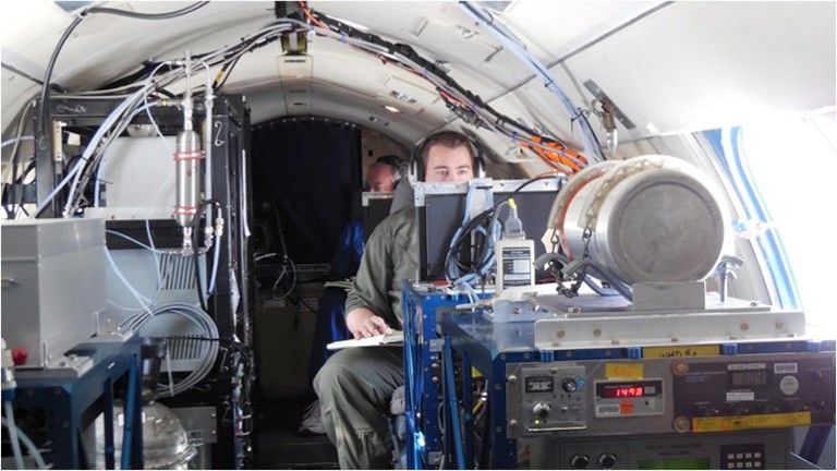 Inside one of three chase planes, NASA scientists Richard Moore and Bruce Anderson analyze exhaust from the DC-8 ahead.