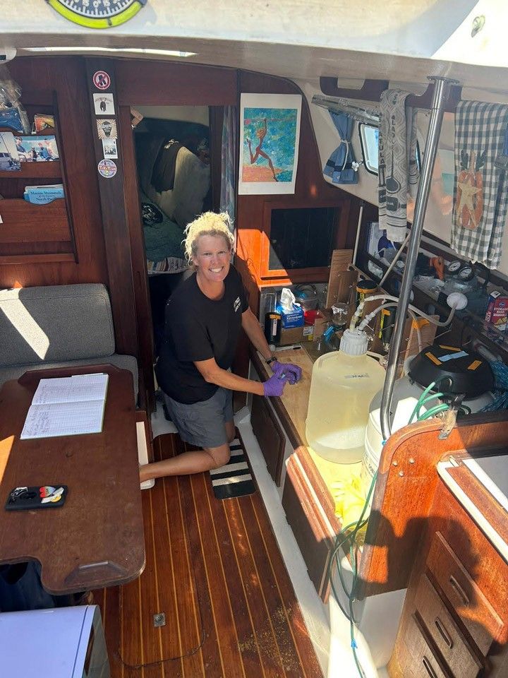 A scientist in the cabin of a sailboat kneels at a workstation filtering water samples.