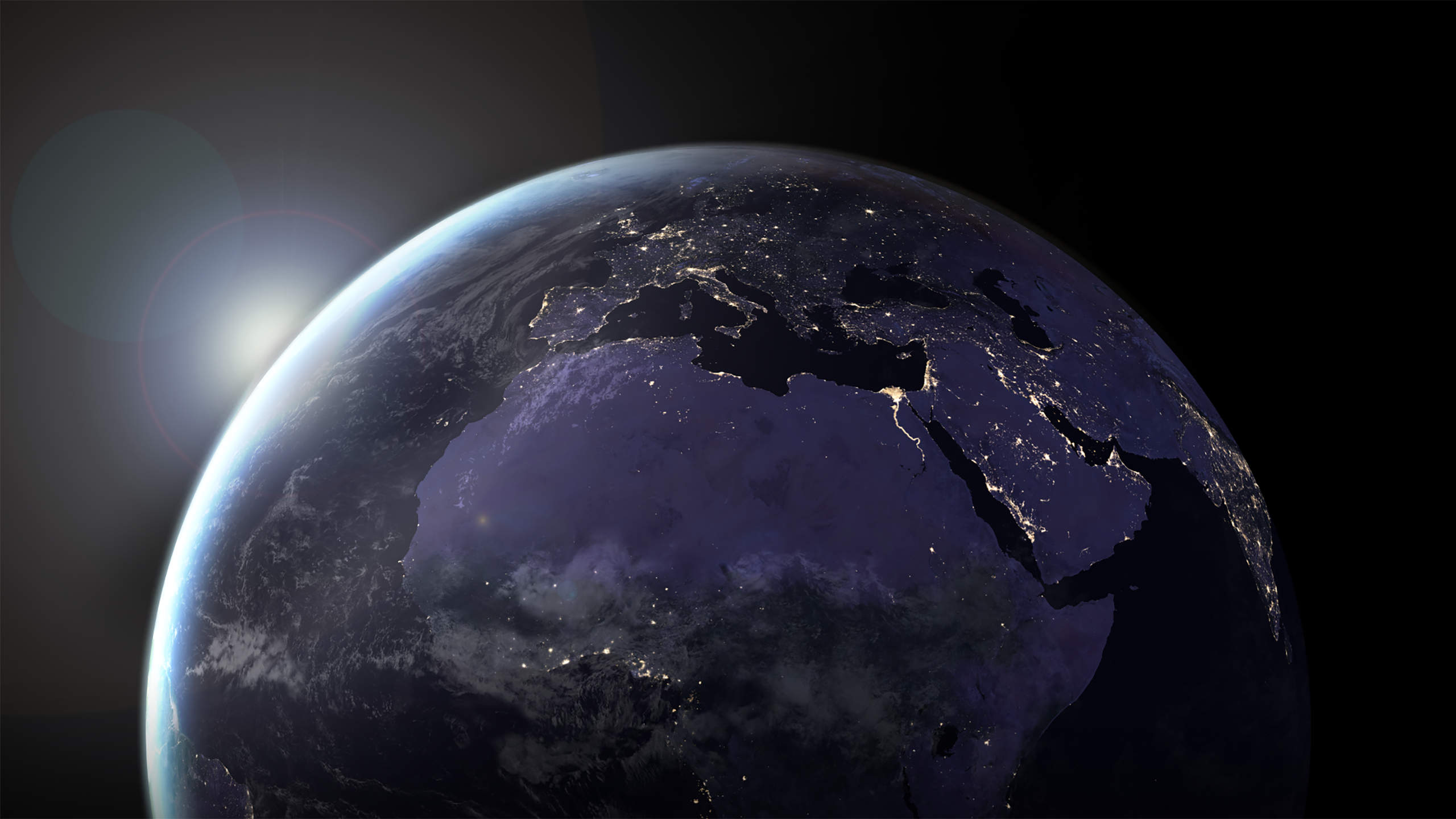 A view of the Earth at night, showing Europe, Africa, and the Middle East, with the Sun peeking over the Earth's limb.